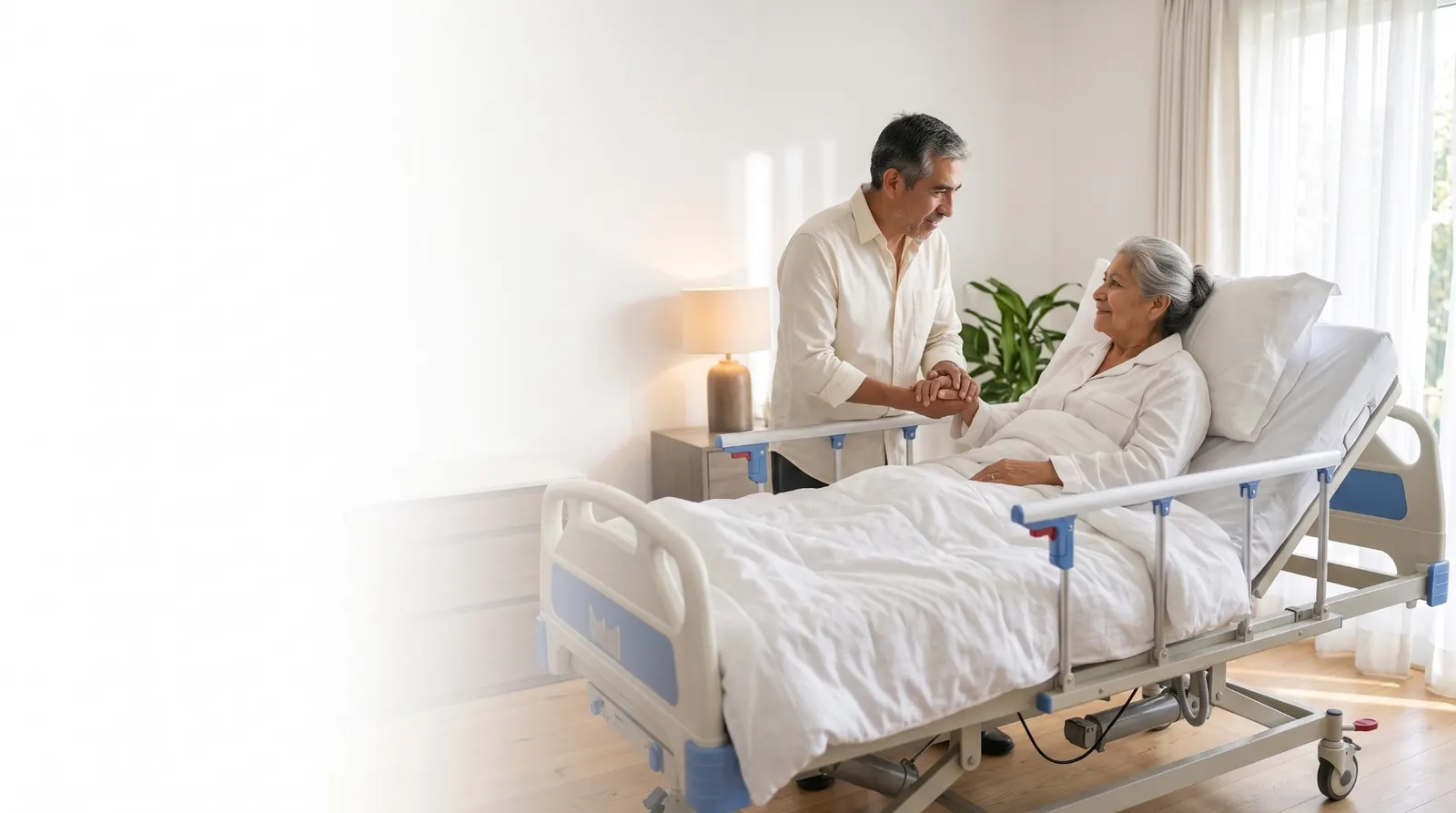 Un hombre toma de la mano a una señora mayor que descansa en una cama de hospital en su casa